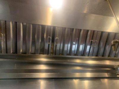 Commercial kitchen stainless steel exhaust hood with vent filters and overhead lighting.