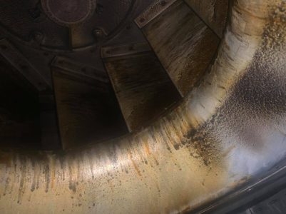 Close-up of a large, industrial metal fan or vent covered in grime and grease stains.