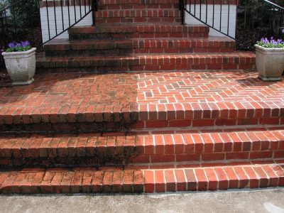 Brick steps with a clear dividing line showing one half clean and the other half covered in dirt and grime.